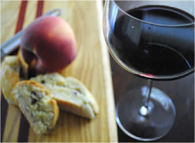 glass of red wine with peach and biscotti