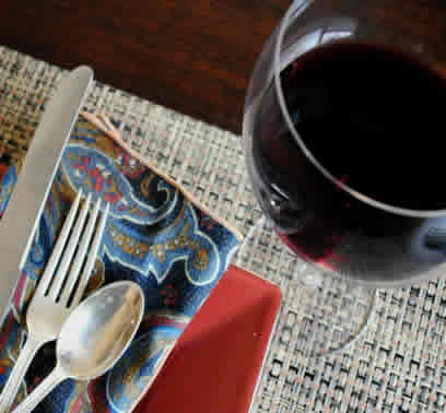 Dinner place setting with glass of red wine.